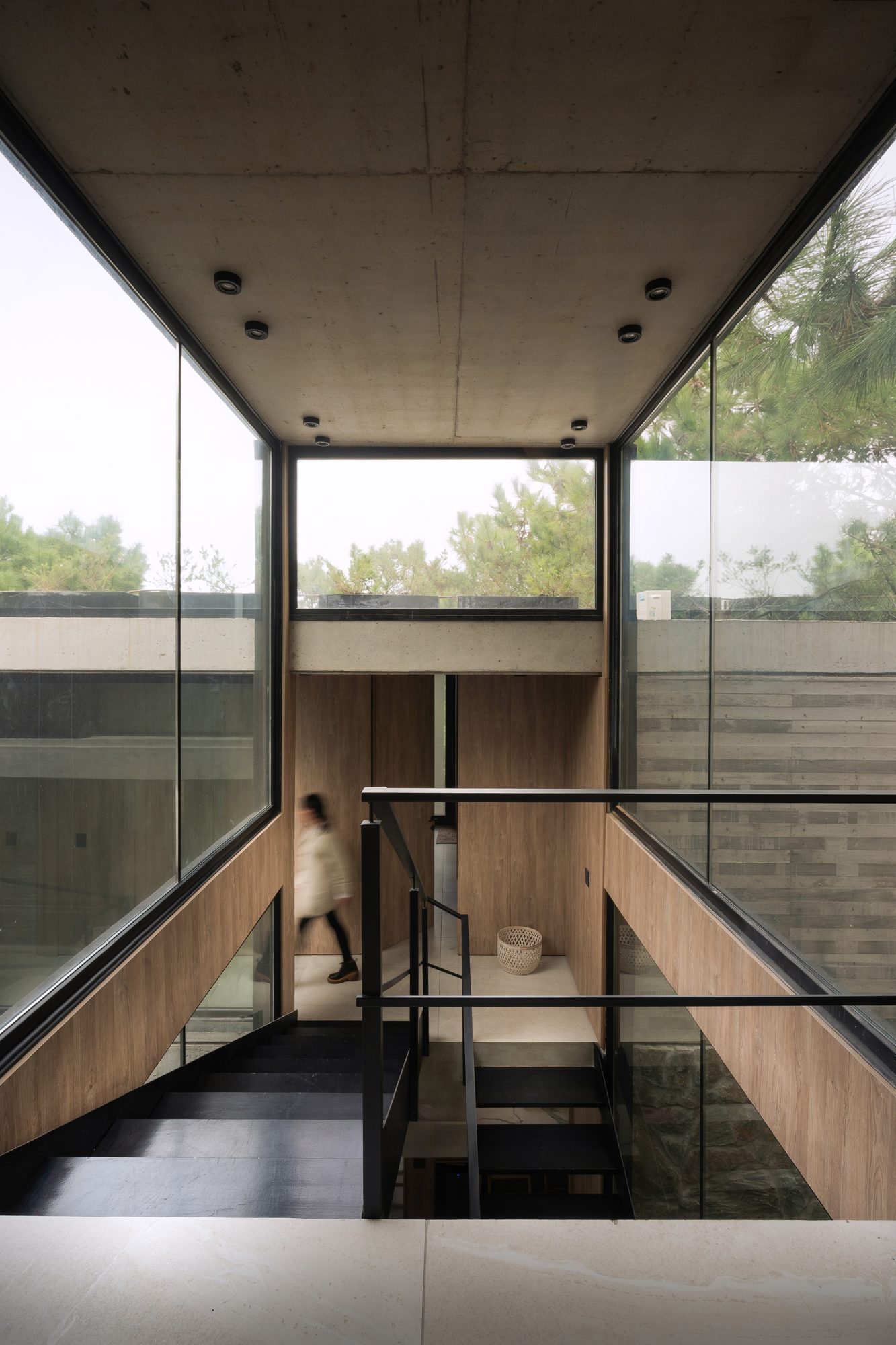 Doble altura vidriada con baranda, vista al pinar desde el entrepiso — CORNER Arquitectura