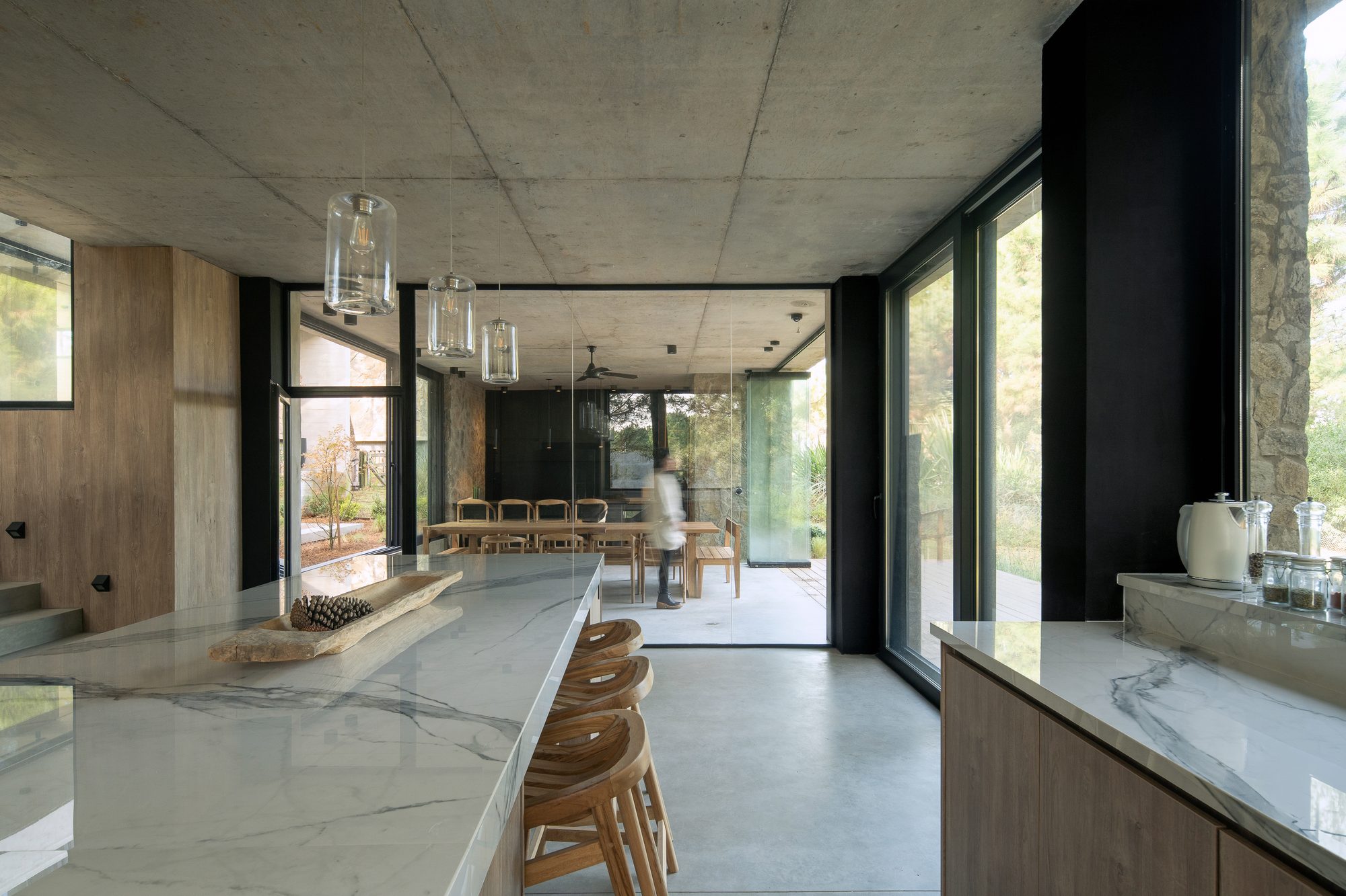 Cocina con isla de mármol y taburetes de madera, abierta al comedor — CORNER Arquitectura