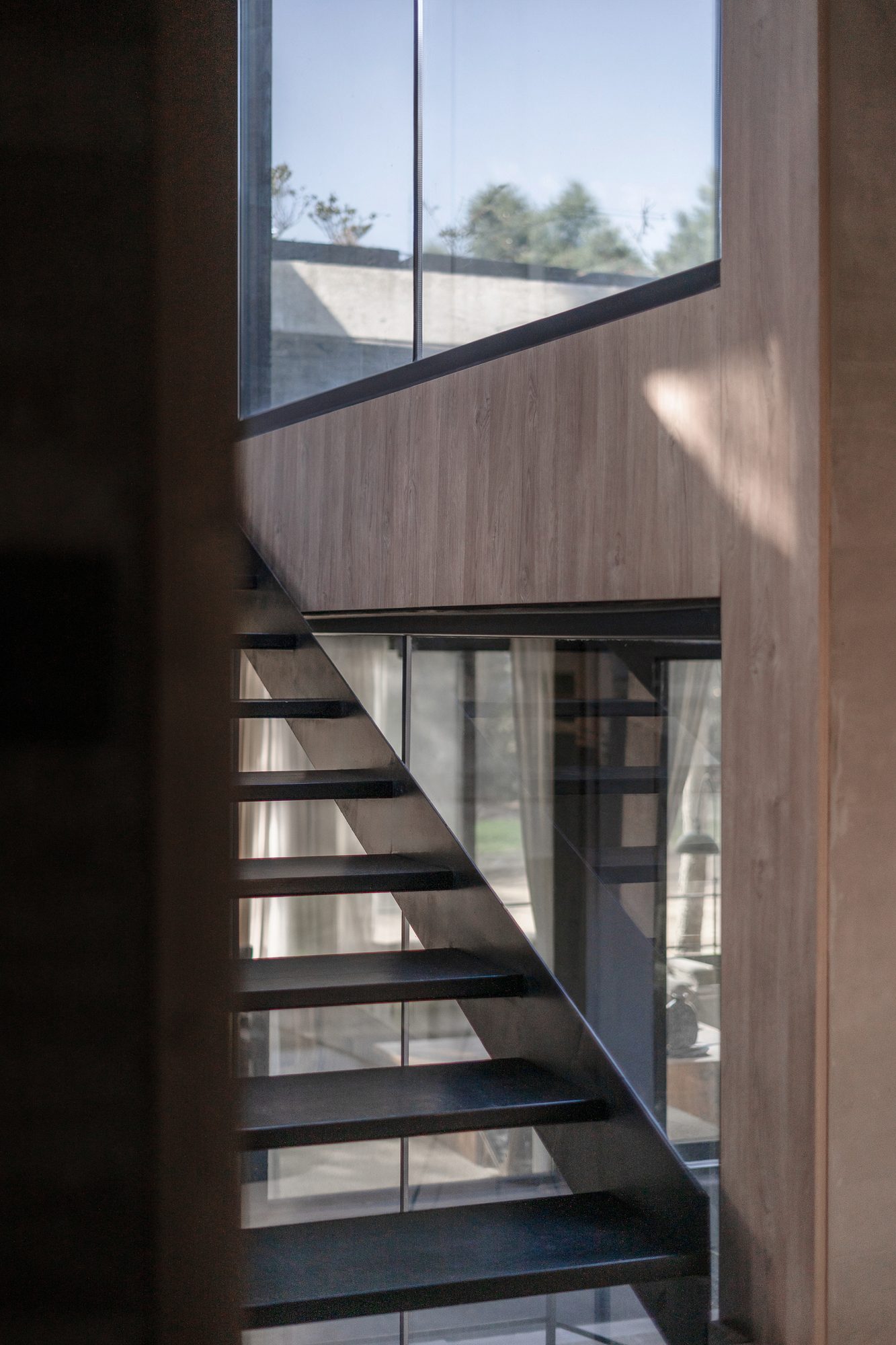 Escalera metálica vista a través del vano, junto al muro de madera — CORNER Arquitectura