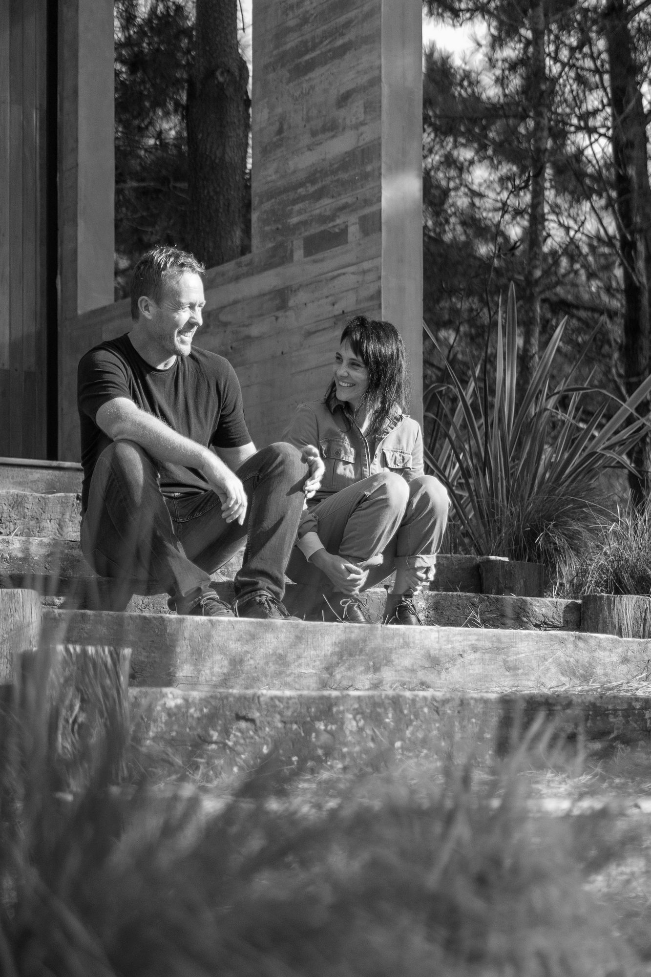 Dos integrantes del estudio conversando en un escalón de hormigón, durante una visita de obra en el pinar — CORNER Arquitectura