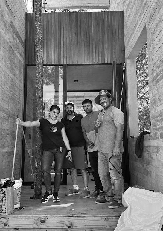 El equipo reunido en el pasillo de hormigón visto de una obra terminada — CORNER Arquitectura