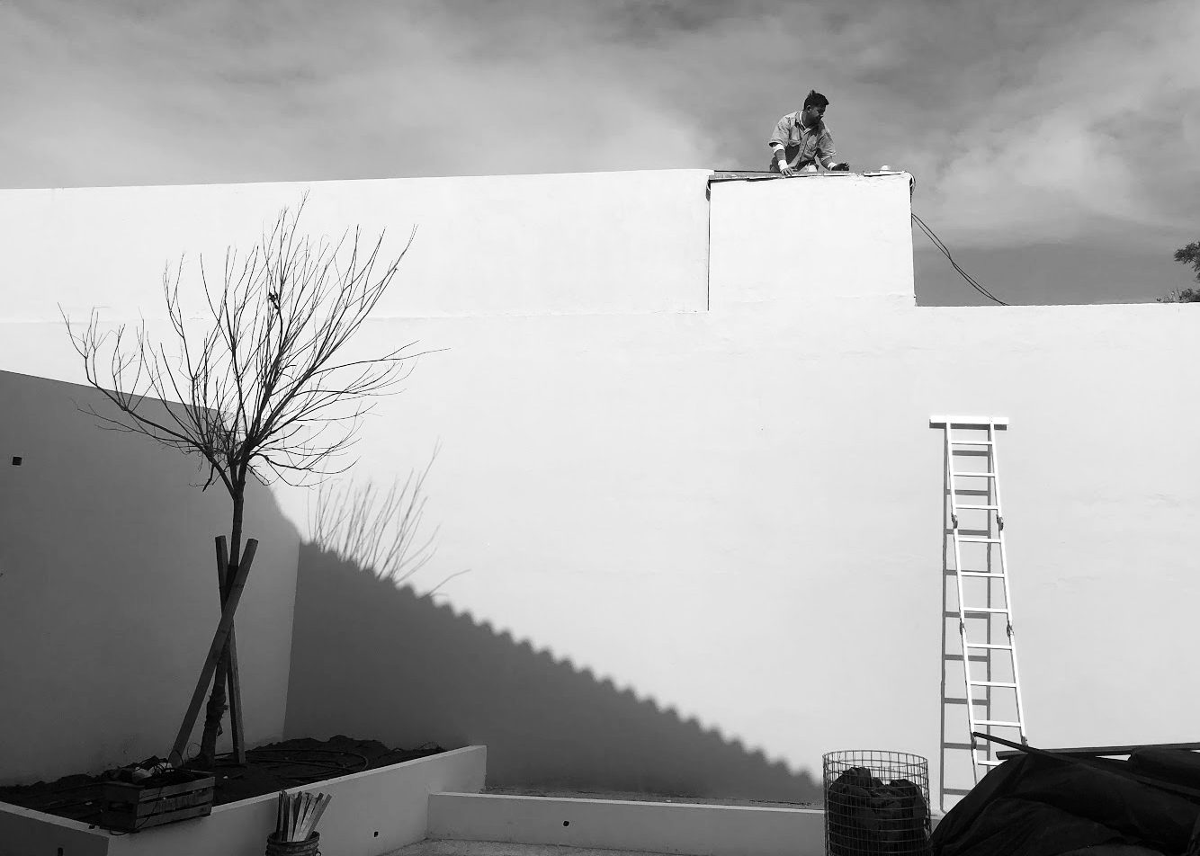 Obra en marcha: muro blanco, escalera apoyada y una persona trabajando sobre la cubierta — CORNER Arquitectura