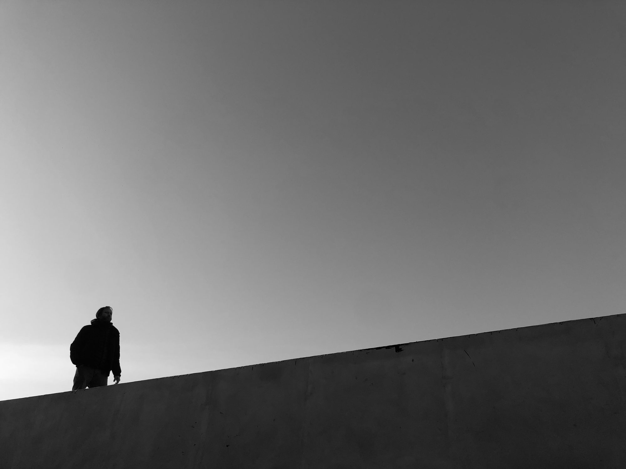 Silueta caminando sobre el talud de un terreno, recortada contra el cielo — CORNER Arquitectura